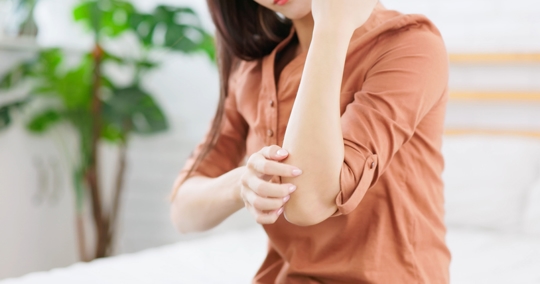 Girl itching arm due to mosquito bite.